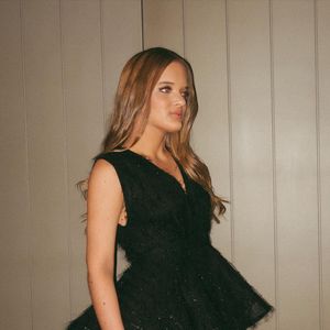 Look é "feito em chiffon transparente com plumas, com uma base de crepe, com o decote em V, peplum pregueado com crinol na barra, e saia godê rodada", segundo a marca