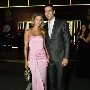 Carol Dias e Kaká: Carol optou por um vestido longo tomara que caia rosa-quartzo em cetim, com nó drapeado na cintura e fenda com caimento fluido; Kaká vestiu um terno cinza-chumbo com camisa branca e gravata rosa-claro em tom coordenado