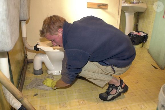 Príncipe William aparece ajoelhado e em posição de quatro, enquanto limpa um vaso sanitário. Foto foi tirada no Chile durante um trabalho voluntário