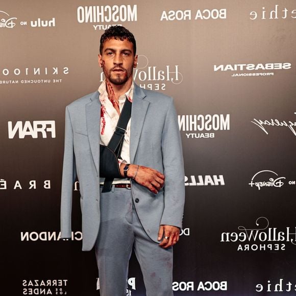 Henrique Barreiras veste um fato azul-claro com camisa branca desabotoada e sapatos mocassins castanhos de camurça. A produção de estilo dramático inclui manchas artificiais de sangue na camisa, no fato, no pescoço e nas mãos, acompanhadas por um braço imobilizado com uma tipoia preta
