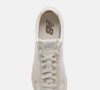 Para quem prefere produções clássicas e discretas, o New Balance 471 branco é uma alternativa para combinar com calças jeans bege, suéteres neutros e acessórios prateados em looks inspirados no estilo old money