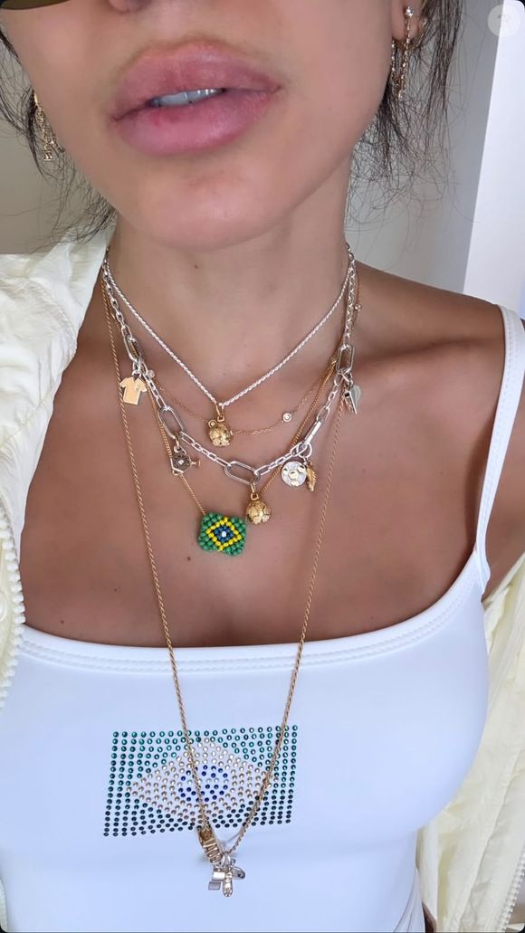 Com regata branca adornada por uma bandeira do Brasil em strass, maxi colares inspirados no futebol e jorts clara, Anitta apostou em uma produção descontraída que já está chamando atenção dos fãs.