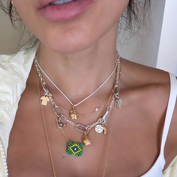 Com regata branca adornada por uma bandeira do Brasil em strass, maxi colares inspirados no futebol e jorts clara, Anitta apostou em uma produção descontraída que já está chamando atenção dos fãs.