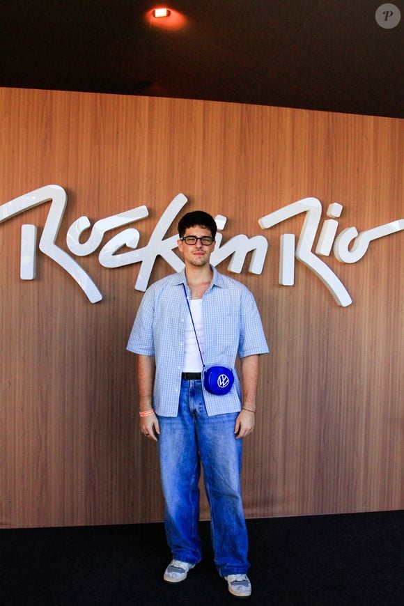 Igor Cosso: o ator veste uma camisa de mangas curtas em xadrez miúdo azul e branco, usada aberta sobre regata branca canelada ajustada. O look é completado por calça jeans de modelagem reta e lavagem média, tênis branco e uma bolsa tiracolo azul-bic redonda com o logotipo da Volkswagen