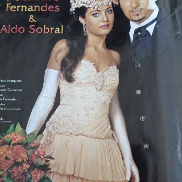 2.Vestido champagne 

Uma proposta não convencional para noivas da época: em vez do branco puro, o estilista trouxe o champagne rosado. O busto tem bordados florais tridimensionais e pedrarias delicadas, que descem em direção à cintura. A saia em camadas plissadas traz movimento e leveza, quase como pétalas sobrepostas. As luvas longas brancas alongam a silhueta e dão um toque aristocrático. É um vestido romântico, sensual e perfeito para quem queria fugir do óbvio.