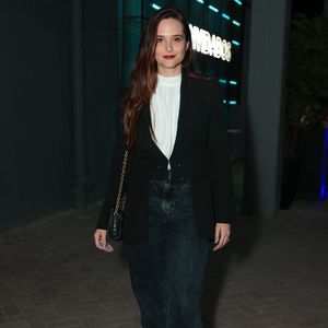 Juliana Paiva apostou em uma alfaiataria sóbria e moderna ao vestir um blazer preto bem estruturado sobre uma blusa branca de gola alta. Para equilibrar a formalidade, a atriz escolheu uma calça jeans reta em lavagem escura e um par de botas pretas de solado tratorado. Ela completou a produção elegante com uma bolsa tiracolo preta com alça de corrente dourada e batom vermelho marcante