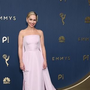 Emilia Clarke: apostou no minimalismo romântico com um vestido longo tomara que caia em tom rosa-pálido, marcado pela estrutura ajustada e minimalista no corpo que se desdobra em uma capa fluida que se estende até o chão formando uma cauda delicada. O modelo traz pequenos detalhes de laços nas laterais do quadril. O visual foi arrematado por um penteado preso polido com risca lateral, lábios vermelhos vibrantes e joias discretas