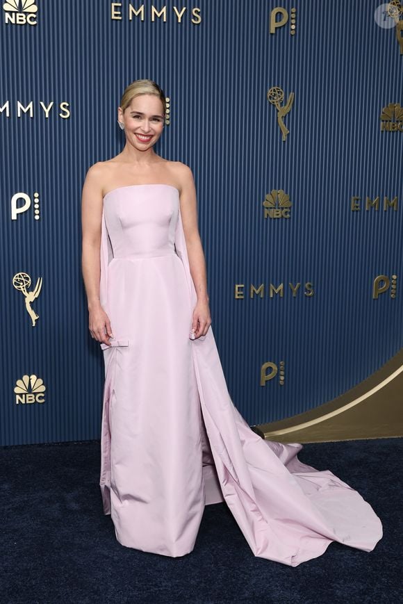 Emilia Clarke: apostou no minimalismo romântico com um vestido longo tomara que caia em tom rosa-pálido, marcado pela estrutura ajustada e minimalista no corpo que se desdobra em uma capa fluida que se estende até o chão formando uma cauda delicada. O modelo traz pequenos detalhes de laços nas laterais do quadril. O visual foi arrematado por um penteado preso polido com risca lateral, lábios vermelhos vibrantes e joias discretas