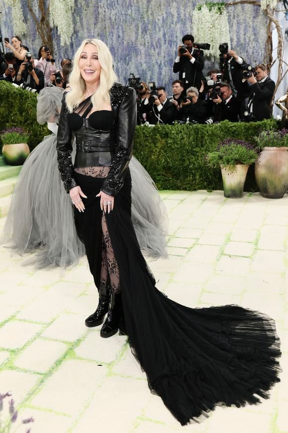 'Do you believe?' Cher compareceu ao Met Gala 2026 com um look rocker ousado: corset de couro com aplicações, meia-calça de renda e uma cauda de tule preto para arrematar
