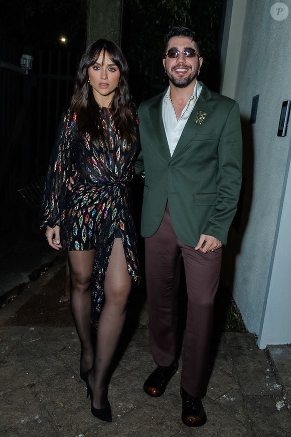 Rafa Kalimann escolheu um vestido curto de paetês com estampas coloridas, combinado a meia-calça preta e scarpin, enquanto Nattan apostou em blazer verde e calça marrom