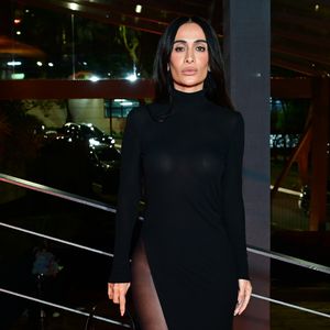Maria Braz: usou um vestido longo preto de gola alta e mangas compridas, caracterizado por uma fenda lateral profunda que vai até a linha do quadril. O visual é complementado por meia-calça preta fina e uma bolsa preta estruturada de ombro com detalhe metálico dourado
