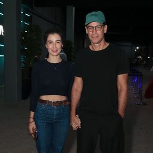 Marjorie Estiano apostou em um visual alinhado e casual ao lado do companheiro, vestindo um top cropped azul-marinho de mangas compridas e jeans de cintura alta com vinco frontal. Ela completou o look com cinto de couro marrom e sapatos num tom terroso elegante. Ao seu lado, ele vestia um look monocromático preto com camiseta básica, calça solta, tênis e boné verde