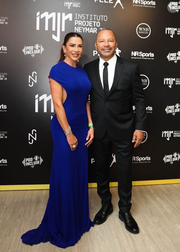 Neymar Pai e Mariane Bernardi: O empresário vestiu um terno clássico preto com camisa social branca e gravata preta fina; já sua companheira destacou-se em um vestido longo azul-caneta (ou azul-bic), de corte ajustado, mangas curtas, cauda fluida e recorte vazado (cut-out) lateral no peito e na cintura
