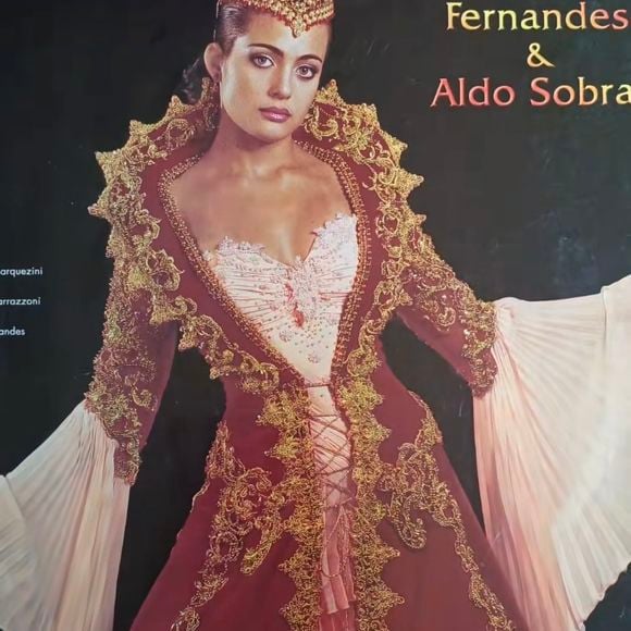 5. Vestido vermelho bordô

Um dos mais ousados da coleção! Inspirado em cortes medievais e palacianos, o vestido foge totalmente do branco. O tom vinho profundo, combinado com bordados dourados riquíssimos, cria um visual imperial. O corpete com amarração central valoriza a cintura, e as mangas em chiffon plissado trazem leveza ao conjunto. A coroa dourada transforma a noiva em uma verdadeira deusa. Uma peça para quem queria marcar época e desafiar tradições.