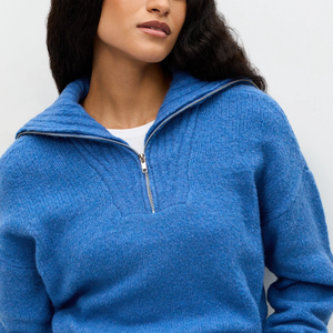 Com textura discreta e gola alta estruturada, o modelo prova que o azul cerúleo continua fashionista