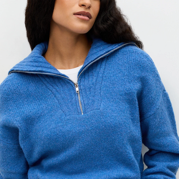 Com textura discreta e gola alta estruturada, o modelo prova que o azul cerúleo continua fashionista