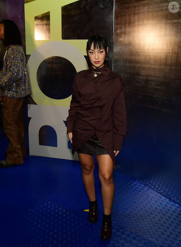 Rio Fashion Week 2026: a atriz Ana Hikari aliou uma camisa comprida marrom com uma saia micro preta