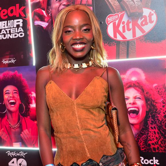 Apartamento de Clara Moneke: suíte da atriz conta com tapete e guarda-roupa acinzentados, roupa de cama creme e cortinas brancas