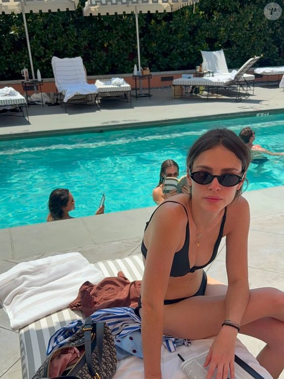 Em um dos cliques da viagem, Isabelle Drummond aparece aproveitando a piscina com uma produção casual que reúne camisa branca, short de poá e chinelo. Na imagem, a bolsa chama atenção e é bastante semelhante à D-Journey, da Dior, criando um contraste entre o visual descontraído e o acessório de luxo
