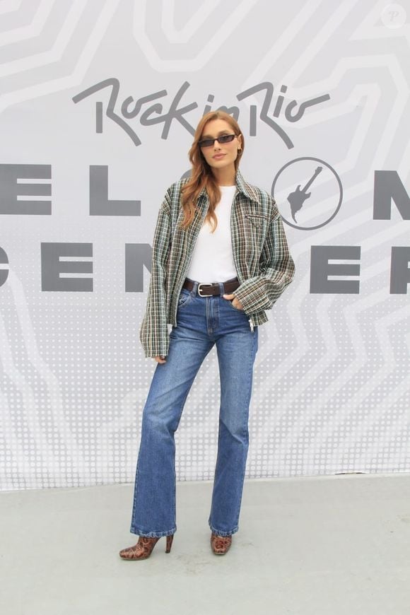 A quarta inspiração vem de Sasha Meneghel e aposta na combinação de tweed, t-shirt e jeans wide leg. A produção reúne jaqueta bomber estruturada de tweed xadrez oversized, camiseta branca básica de gola careca e calça jeans reta ou wide leg de cintura alta, acompanhada de cinto com fivela metálica