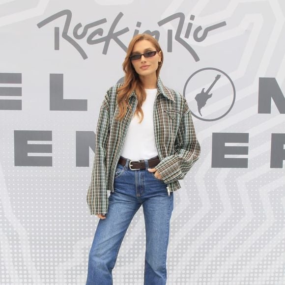 A quarta inspiração vem de Sasha Meneghel e aposta na combinação de tweed, t-shirt e jeans wide leg. A produção reúne jaqueta bomber estruturada de tweed xadrez oversized, camiseta branca básica de gola careca e calça jeans reta ou wide leg de cintura alta, acompanhada de cinto com fivela metálica