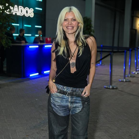 Duda Beat: veste blusa preta de decote degagê frente única com calça jeans de modelagem ampla e sobreposição em couro estilo chaps, finalizada com botas tratoradas