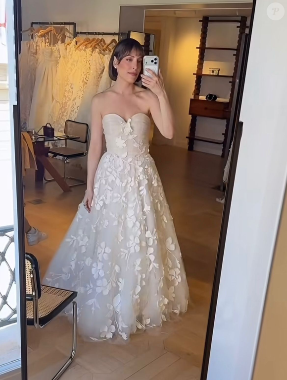 5. Linha A com aplicações florais em relevo (3D): vestido de noiva no corte linha A com corpete de decote coração levemente drapeado. O tecido de tule traz aplicações de flores e folhas em relevo 3D feitas do mesmo tecido, distribuídas de forma contínua a partir do peito até toda a extensão da saia volumosa