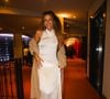 Gabriela Loran escolheu um vestido branco longo, com decote halter, modelagem ajustada e drapeados na saia. Um casaco felpudo bege e sandálias metalizadas completaram o visual