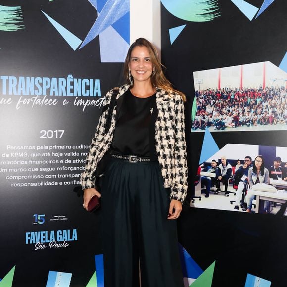 Luciana Cardoso, esposa de Faustão usa look elegante e versátil: um blazer de tweed em preto e branco sobre um top de seda preto. Ela combinou as peças com calças pantalonas de cintura alta em verde esmeralda, realçadas por um cinto de couro preto com fivela metálica ornamentada. Ela completou a produção com sandálias pretas de salto e brincos longos e brilhantes