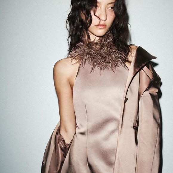 A peça que é a cara da influencer Naiane Amaral, em tecido que lembra cetim com acabamento acetinado chama atenção pela gola halter adornada com plumas, criando um visual sofisticado e ousado na medida certa