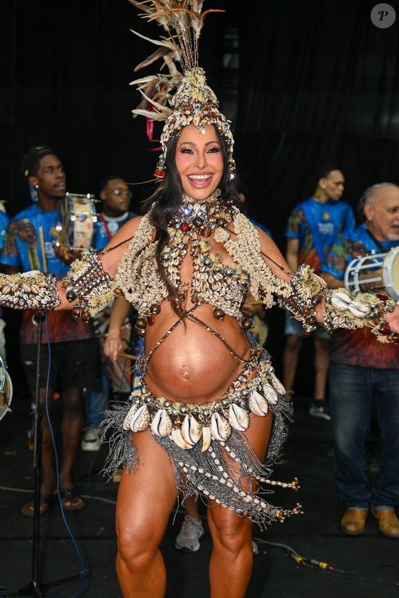 Grávida de oito meses, Sabrina Sato escolhe um figurino com franjas prateadas, búzios pendentes e top estruturado para mais uma noite de samba na Vila Isabel