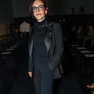 Maria Prata optou por um terno preto sofisticado de alfaiataria com lapelas acetinadas em estilo smoking, sobreposto a uma blusa de gola alta preta com gargantilha metálica discreta. A calça reta de corte amplo completa o visual monocromático, finalizado com óculos de armação preta marcante e sapatos escuros de bico fino