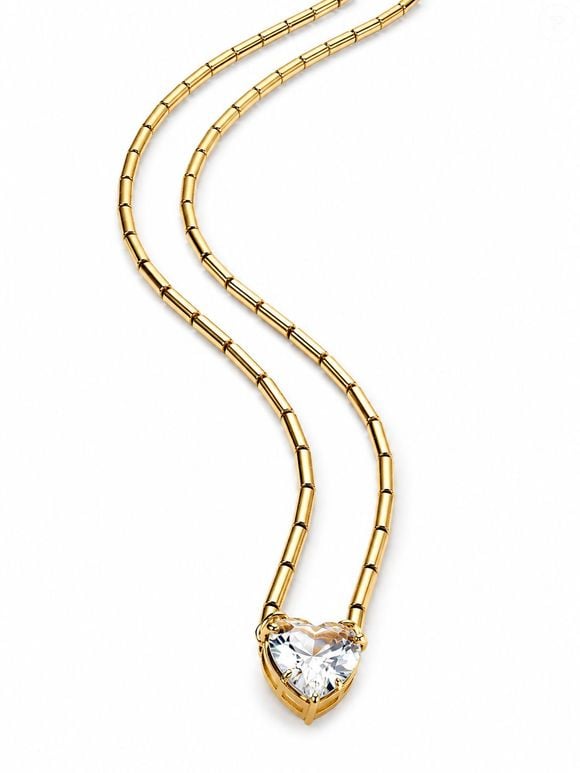 Gargantilha H.MARIA folheada a ouro com pedra cristal lapidada em formato de coração. Corrente estruturada em canutilhos metálicos, trazendo uma estética contemporânea e sofisticada; valor da joia: R$ 309,60