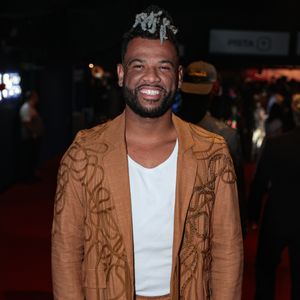 Rene Silva optou por um conjunto de linho em tom ferrugem que une conforto e elegância. O blazer longo possui aplicações de cordões bordados em padrões orgânicos que descem até a barra, criando um efeito visual de textura única. A calça, com amarração de cordão e detalhe de pérola na ponta, reforça o aspecto artesanal da peça