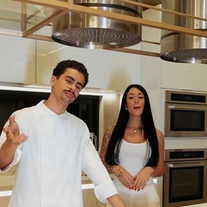 A cozinha tecnológica, usada por Rayane Figliuzzi em seus conteúdos de receitas, reúne cooktop de indução embutido, coifas de inox suspensas e eletros integrados em acabamento sofisticado