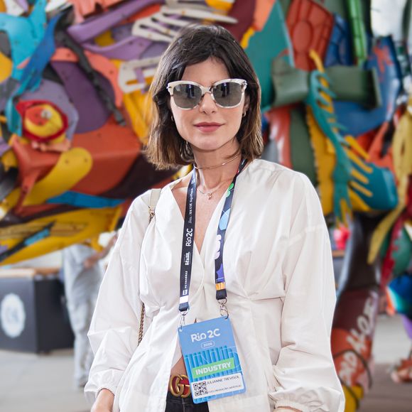 O visual da atriz Julianne Trevisol no Rio2C traz uma camisa branca texturizada com mangas bufantes e decote em "V", equilibrada por uma calça jeans preta de modelagem ampla