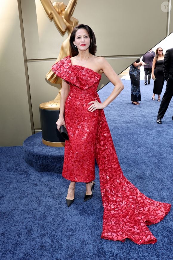 Jackie Tohn: vestido de comprimento mídi em tom vermelho-vivo, totalmente coberto por sequins e lantejoulas florais. O modelo assimétrico de um ombro só exibe um babado estruturado no decote e uma cauda longa lateral que se estende até o chão. A produção é finalizada com scarpins pretos e batom vermelho marcante