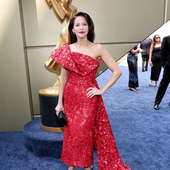 Jackie Tohn: vestido de comprimento mídi em tom vermelho-vivo, totalmente coberto por sequins e lantejoulas florais. O modelo assimétrico de um ombro só exibe um babado estruturado no decote e uma cauda longa lateral que se estende até o chão. A produção é finalizada com scarpins pretos e batom vermelho marcante