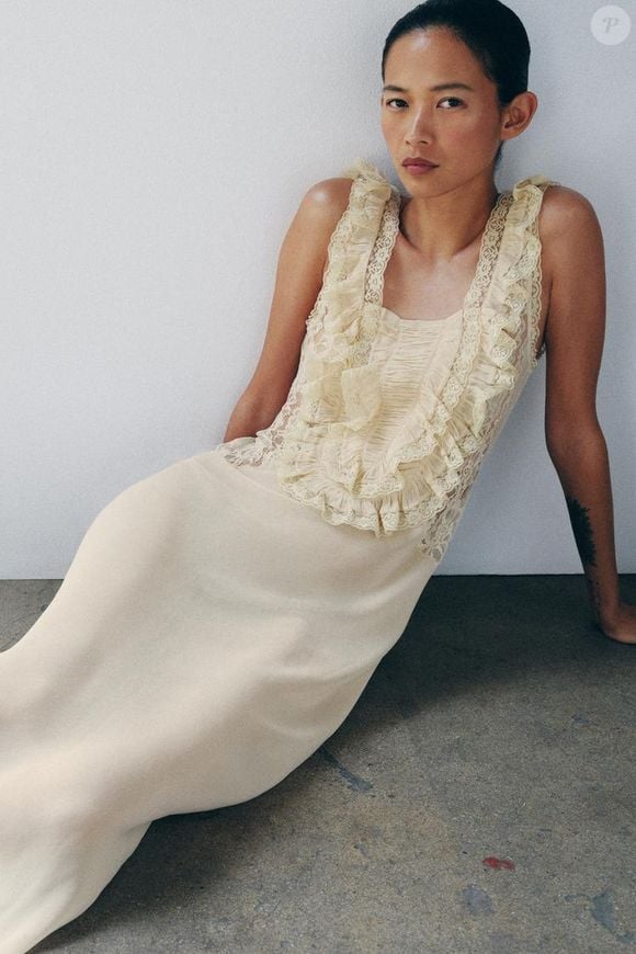 A Zara traz uma versão sofisticada da tendência com o Vestido Longo Drapeado em Renda, disponível por R$ 739, unindo fluidez, babados e detalhes rendados