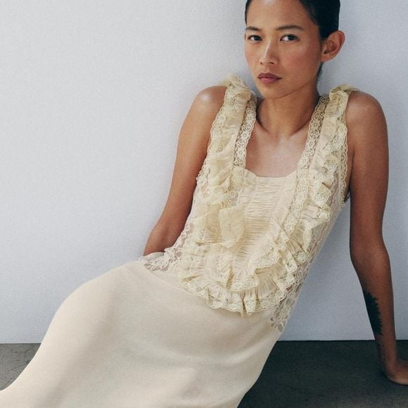 A Zara traz uma versão sofisticada da tendência com o Vestido Longo Drapeado em Renda, disponível por R$ 739, unindo fluidez, babados e detalhes rendados