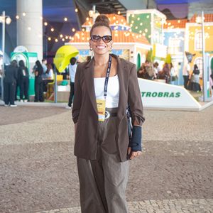 Atriz e cantora, Jeniffer Nascimento, interpreta a estética corpcore com uma forte pegada streetwear. Ela combinou um blazer alongado marrom-chocolate com calça de alfaiataria ampla em tom cáqui, equilibrando a sobriedade das peças com uma regata branca básica e tênis de solado robusto. Óculos de sol de gatinho e um coque alto arrematam o visual com muito estilo