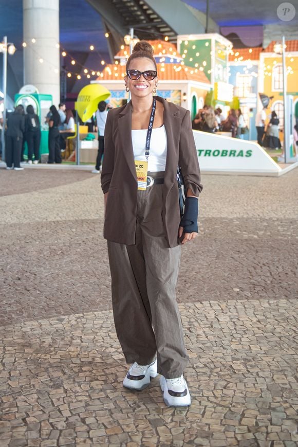 Atriz e cantora, Jeniffer Nascimento, interpreta a estética corpcore com uma forte pegada streetwear. Ela combinou um blazer alongado marrom-chocolate com calça de alfaiataria ampla em tom cáqui, equilibrando a sobriedade das peças com uma regata branca básica e tênis de solado robusto. Óculos de sol de gatinho e um coque alto arrematam o visual com muito estilo