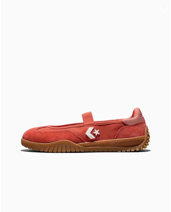 O modelo Converse Run Star Trainer Ballet Flat na cor 'Laranja Mecânica' também apresenta os icônicos logos Star Chevron e Converse, elementos que reforçam a identidade da marca