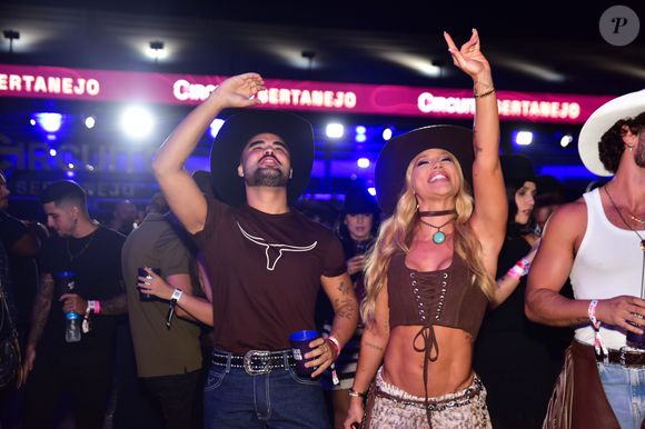Influenciadora exibe top de amarração e saia animal print em visual cowgirl moderno; na imagem, ela curte com Lucas Guedez o Caldas Country 2025