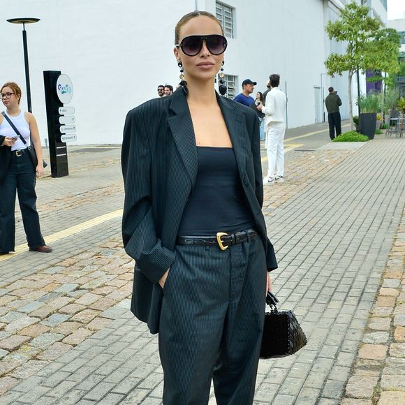 A influenciadora Júlia Rodrigues aliou o blazer com uma camiseta simples - e destaque para as sandálias amarradas sobre a calça!