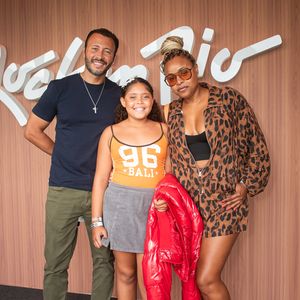 Roberta Rodrigues exibe um conjunto em animal print de oncinha com forte apelo streetwear, composto por jaqueta leve e shorts, combinado a um top cropped preto, tênis esportivo retro e óculos de sol translúcidos, trazendo uma jaqueta puffer vermelha a tiracolo ao lado da família