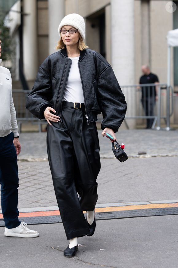 Durante a Semana de Moda de Paris, a modelo Gigi Hadid apareceu usando um par de sapatilhas da marca Mansur Gavriel antes de desfilar para a Miu Miu. O look combinava jaqueta bomber ampla com calça de couro, criando um visual moderno e despretensioso.