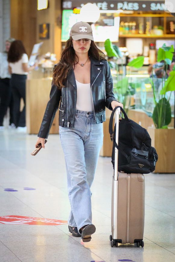 Outro item que chamou atenção foi a bagagem de mão da atriz. Sobre a mala, foi possível identificar uma it bag da Prada