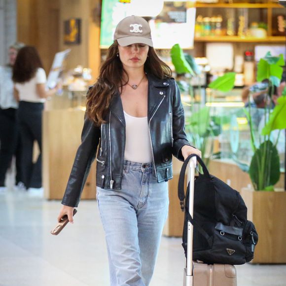 Outro item que chamou atenção foi a bagagem de mão da atriz. Sobre a mala, foi possível identificar uma it bag da Prada