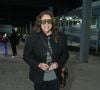 Ana Carolina: usa blazer estruturado preto sobre camiseta verde estampada, calça preta, óculos de armação grande, bolsa transversal e botas pretas com fivelas